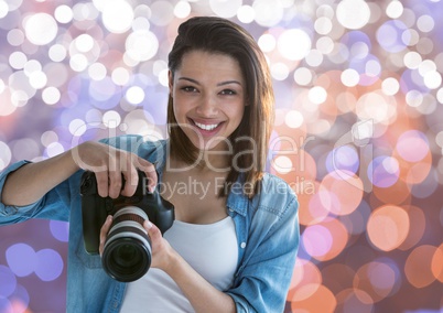 young photographer smiling with the camera on hands. Brown white and blue bokeh background