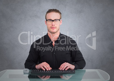 Nerd man at desk against grey wall with grunge overlay