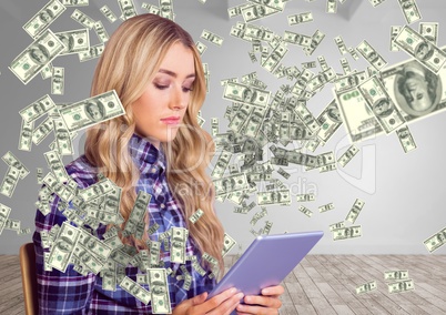 texting money. young woman sit with tablet. Money coming up from tablet.