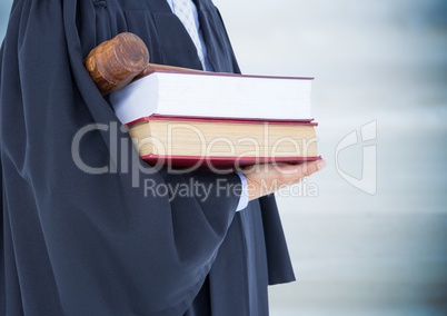 Judge mid section with books and gavel against blurry blue wood panel
