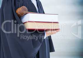 Judge mid section with books and gavel against blurry blue wood panel