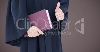 Female judge mid section with book and thumbs up against brown background