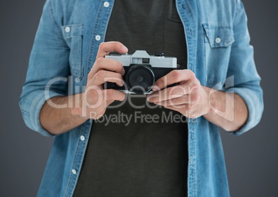 Millennial man mid section with camera against grey background