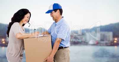 Delivery man giving box to woman against blurry skyline