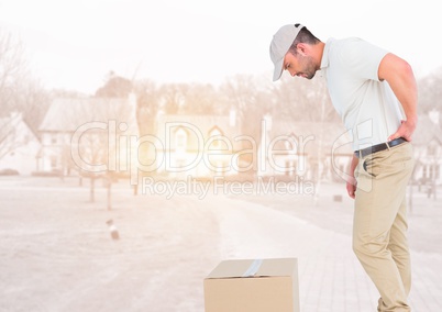 Delivery man looking at box against blurry housing estate with flares