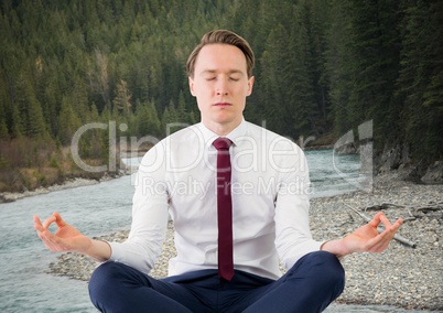 Business man meditating against river