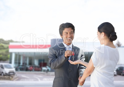 Businessman handing car keys to woman at car auto store