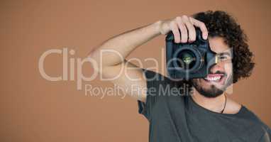 Millennial man with camera against brown background
