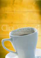 White coffee cup and saucer against blurry yellow wood panel