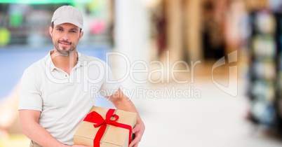 Delivery man with gift against blurry shopping centre