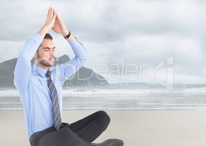 Business man meditating against blurry beach