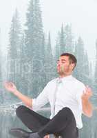 Business man meditating against trees with snow