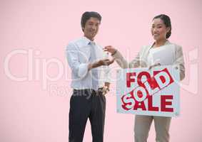 Two people holding For Sale sign and keys in front of vignette
