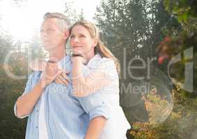 Middle aged couple embracing in forest with flare