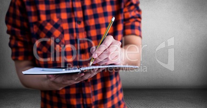 Millennial man mid section with notepad against grey room