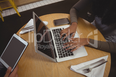 Cropped image of woman using laptop in cafe