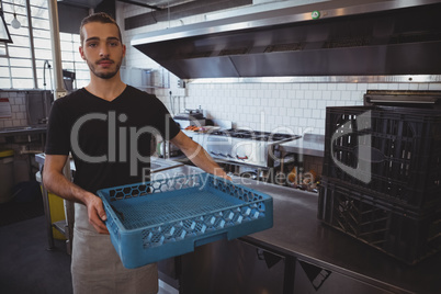 Portrait of waiter holding blue crate in kitchen