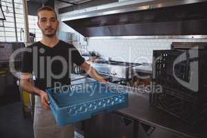 Portrait of waiter holding blue crate in kitchen