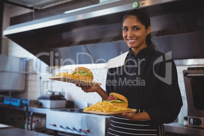 Portrait of waitress with French fries and burger in cafe