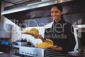 Portrait of waitress with French fries and burger in cafe