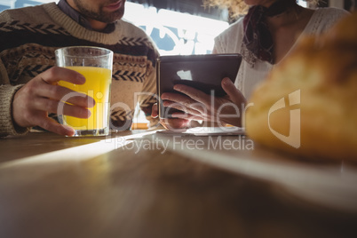 Mid section of woman with man using tablet in cafe