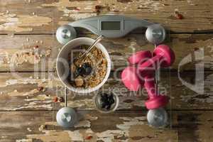Bowl of breakfast and dumbbells on weighing scale