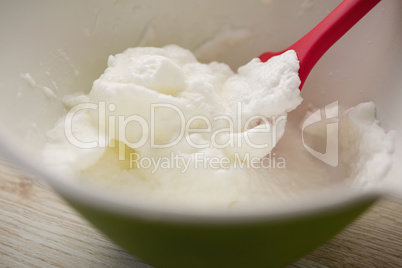 Close up of spatula and whipped cream in bowl