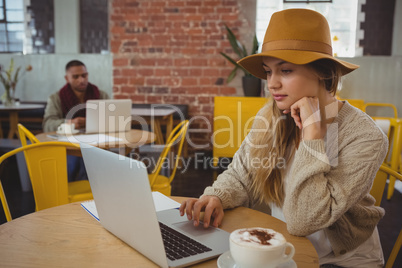 Businesswoman using laptop at table in cafe