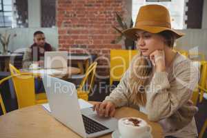 Businesswoman using laptop at table in cafe