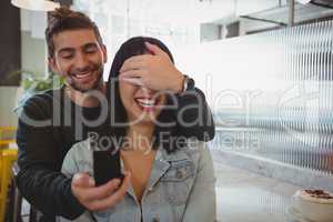 Man covering girlfriend eyes while gifting ring