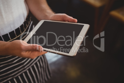 Midsection of waiter holding tablet