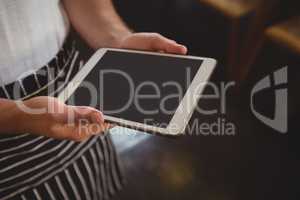 Midsection of waiter holding tablet