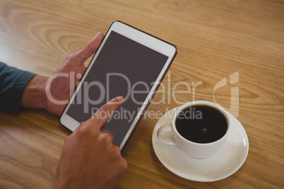 Cropped hands of man with coffee using tablet in cafe