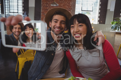Happy man with woman taking selfie at cafe