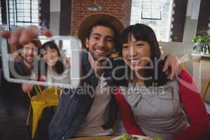 Happy man with woman taking selfie at cafe