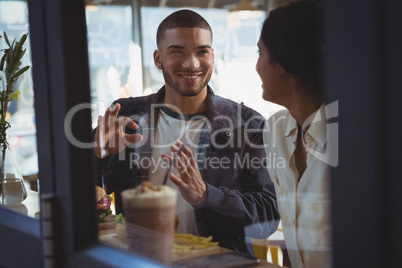 Couple looking each other seen through glass in cafe