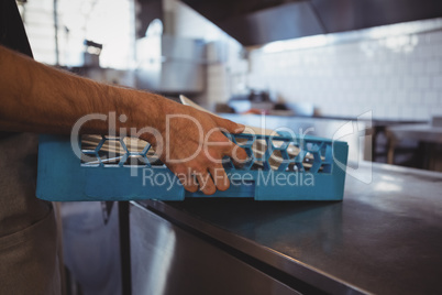 Cropped hand of waiter arranging plates in crate