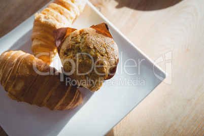 Muffin and croissants served in plate on table