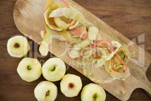 Overhead view of fresh apples by peels on cutting board