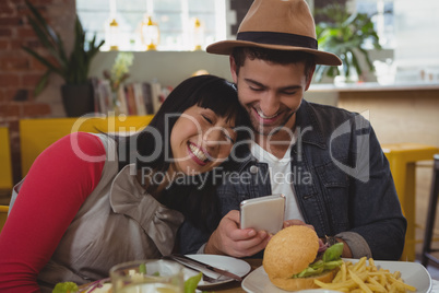 Man with young woman using phone at cafe