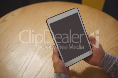 Cropped hand of man holding tablet at table