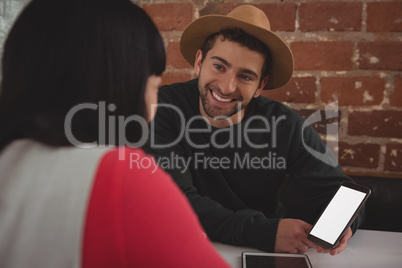 Man with mobile phone looking at girlfriend in cafe