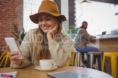 Smiling woman using phone in cafe