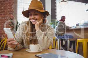 Smiling woman using phone in cafe
