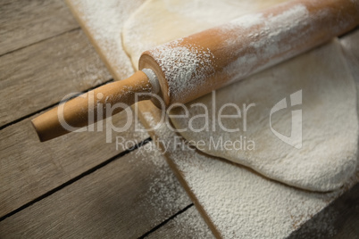 High angle view of rolling pin on rolled dough over cutting board