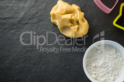 High angle view of dough by flour in bowl