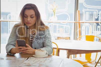 Young woman using phone in cafe