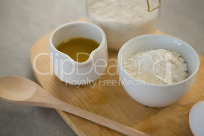 Flour and oil in containers on cutting board