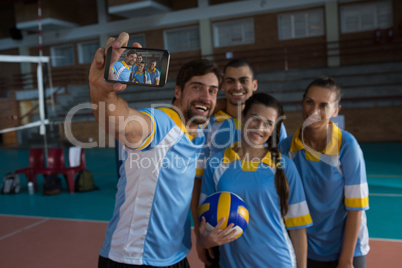 Smiling male volleyball player with team taking selfie