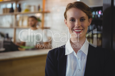 Portrait of happy owner with waiter in background at cafe